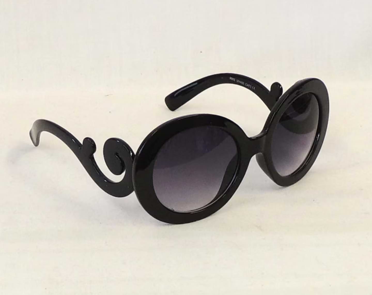 Ariana retro large oval sunglasses with glossy black frames, dark gradient lenses, and dramatic curly temple arms.